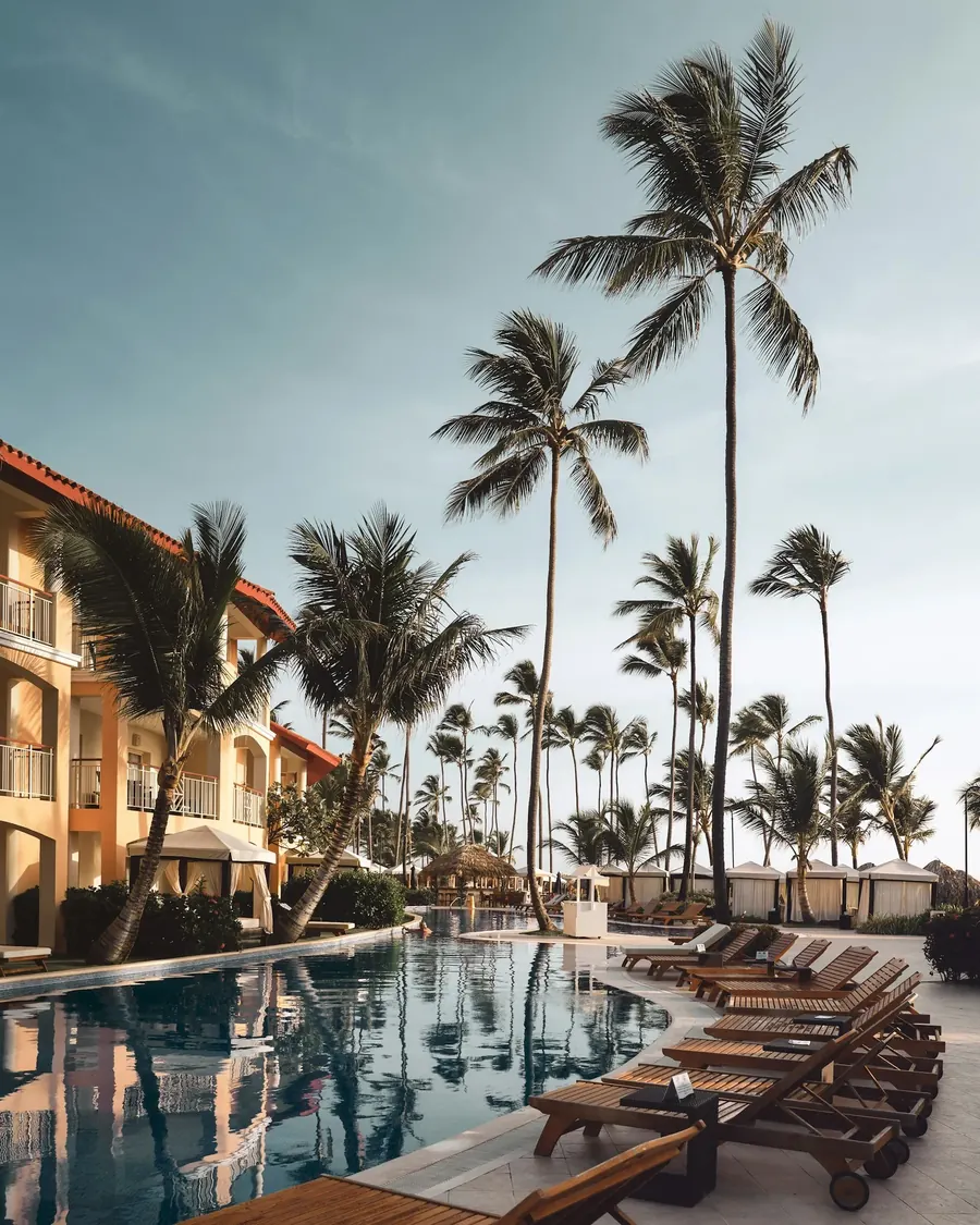 A palm-lined resort pool in golden afternoon light.